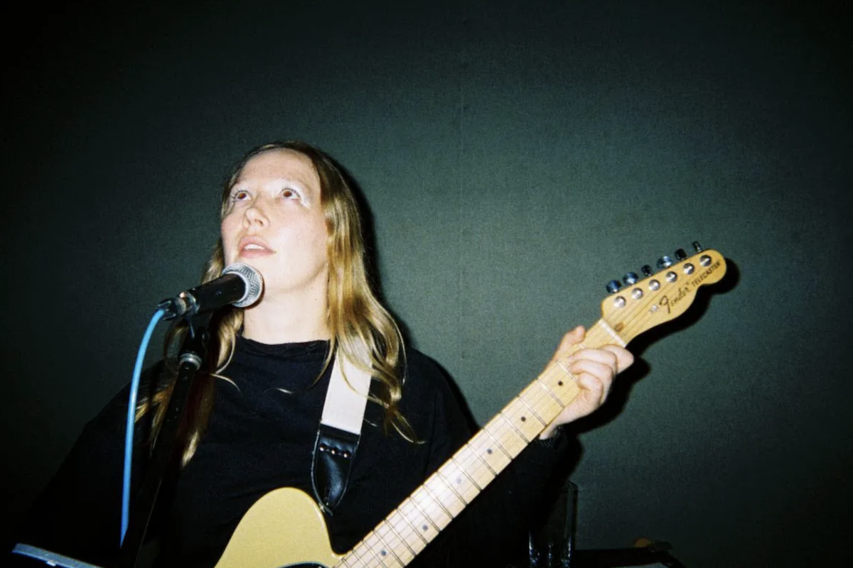 Australian singer-songwriter Julia Jacklin playing a Fender Telecaster electric guitar while singing live into a microphone.
